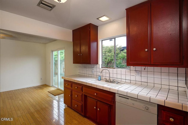 kitchen featuring visible vents, a sink, backsplash, light wood-style floors, and dishwasher