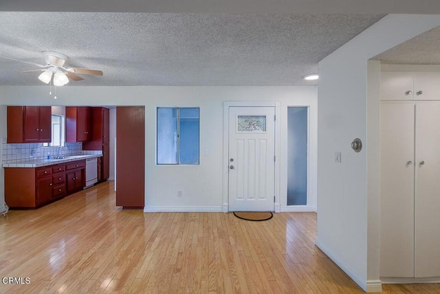 kitchen with tasteful backsplash, dishwasher, light wood-type flooring, a textured ceiling, and a sink