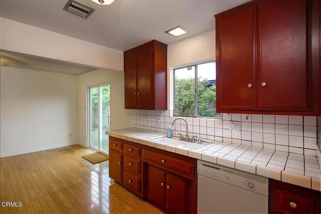 kitchen featuring white dishwasher, a sink, decorative backsplash, baseboards, and visible vents