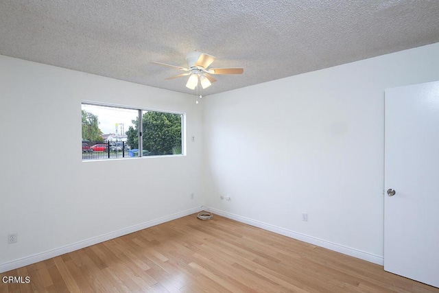 spare room featuring light wood finished floors, baseboards, a textured ceiling, and ceiling fan