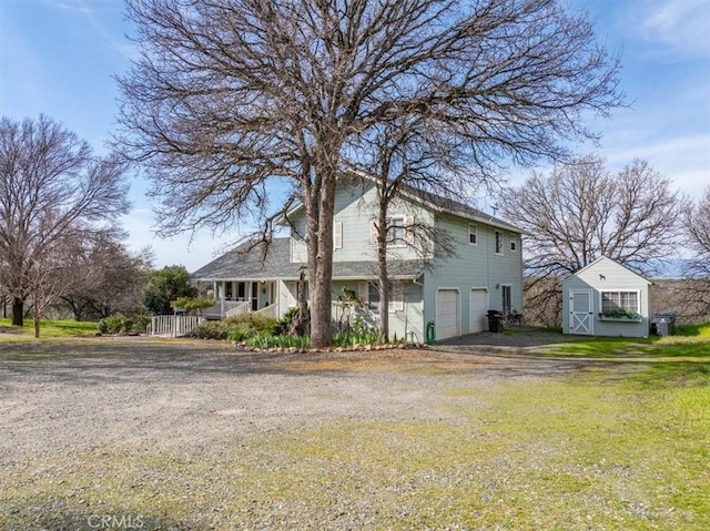 view of home's exterior with a porch, an outbuilding, a garage, and driveway