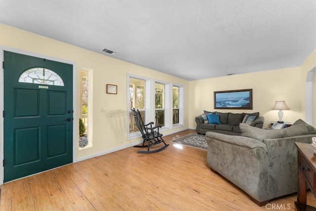 living room with wood finished floors, visible vents, and baseboards