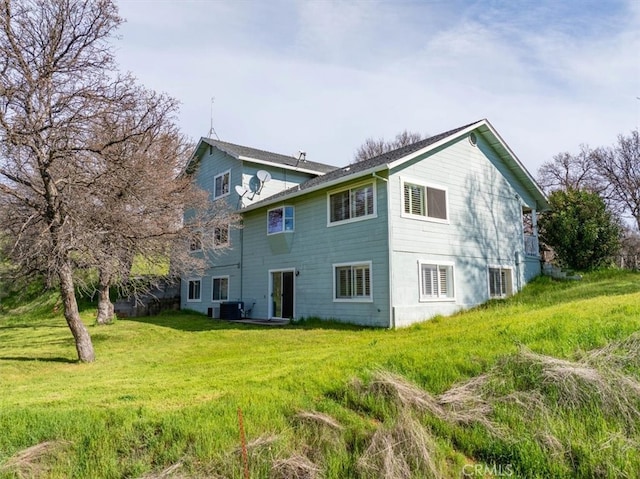 rear view of house featuring a lawn and central AC