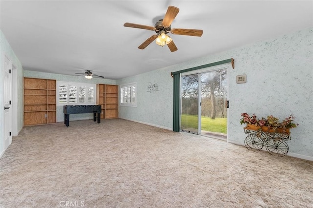 carpeted living room featuring baseboards, wallpapered walls, and a ceiling fan