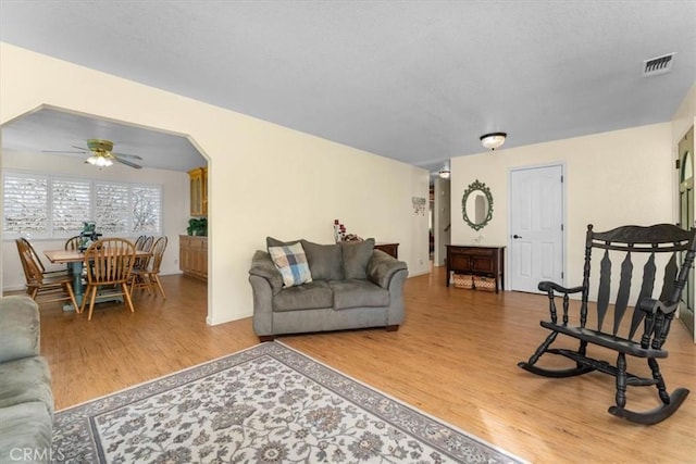 living room featuring visible vents, a ceiling fan, and wood finished floors