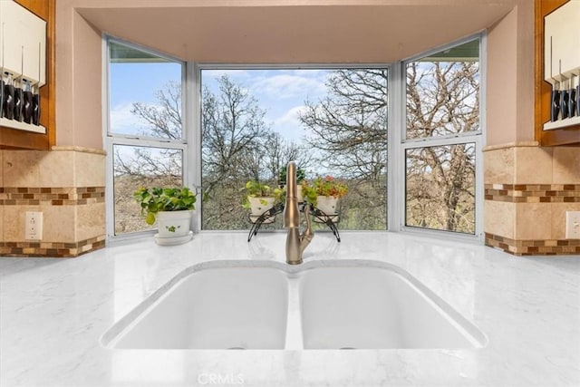 room details with light stone countertops and a sink