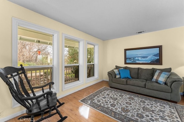 living room with visible vents, baseboards, and wood finished floors