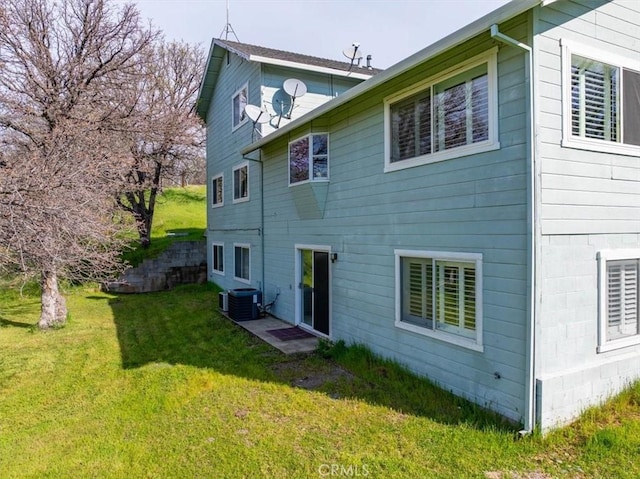 back of house with cooling unit and a lawn