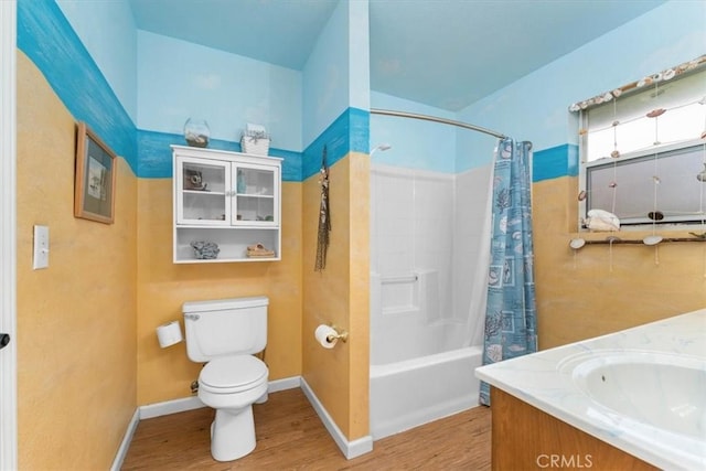 full bathroom featuring toilet, shower / bath combo, wood finished floors, baseboards, and vanity