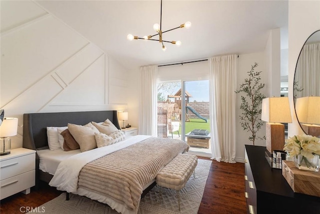 bedroom with dark wood-style floors, an inviting chandelier, a decorative wall, lofted ceiling, and access to exterior