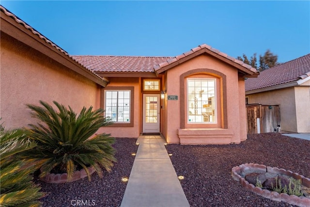 property entrance featuring a tiled roof and stucco siding