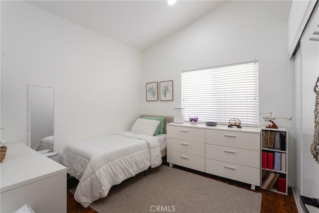 bedroom with dark wood finished floors, a closet, and lofted ceiling