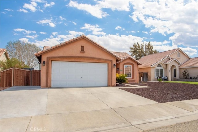 mediterranean / spanish house with stucco siding, a tile roof, fence, concrete driveway, and an attached garage