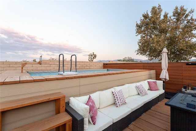 deck at dusk with a fenced in pool, outdoor lounge area, and fence