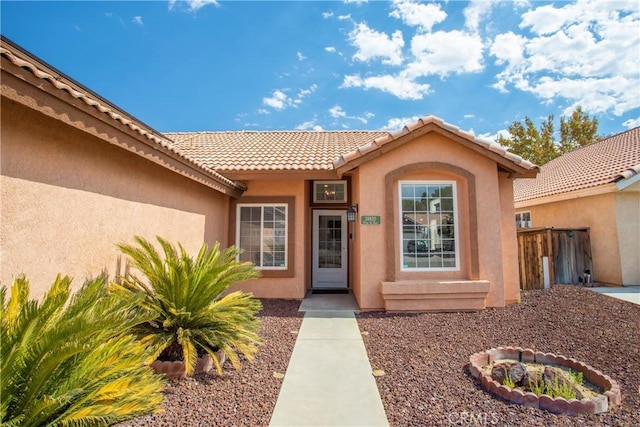 entrance to property featuring a tile roof and stucco siding