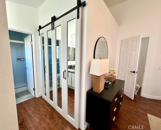 corridor featuring a barn door and dark wood-style flooring