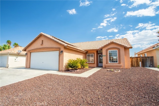 ranch-style house featuring stucco siding, driveway, a garage, solar panels, and a tiled roof