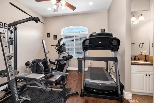 workout area featuring ceiling fan, wood finished floors, baseboards, and a sink