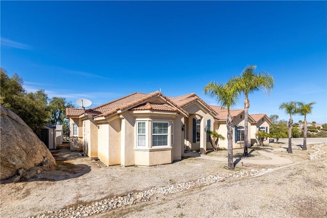 mediterranean / spanish-style home with stucco siding, an outbuilding, a shed, and a tile roof