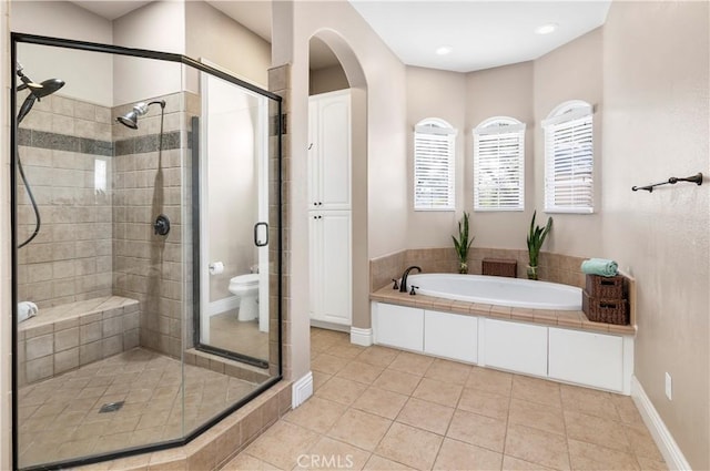 bathroom with a shower stall, a garden tub, baseboards, and tile patterned floors