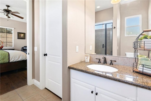 ensuite bathroom with tile patterned floors, a stall shower, connected bathroom, ceiling fan, and vanity