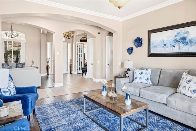 living room featuring ornamental molding, baseboards, arched walkways, and a chandelier