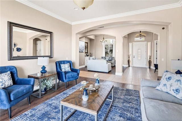 living room featuring arched walkways, a chandelier, crown molding, and wood finished floors