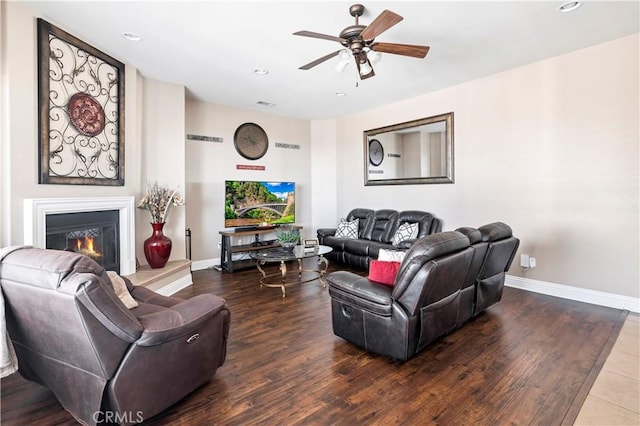 living room with ceiling fan, baseboards, a glass covered fireplace, and wood finished floors