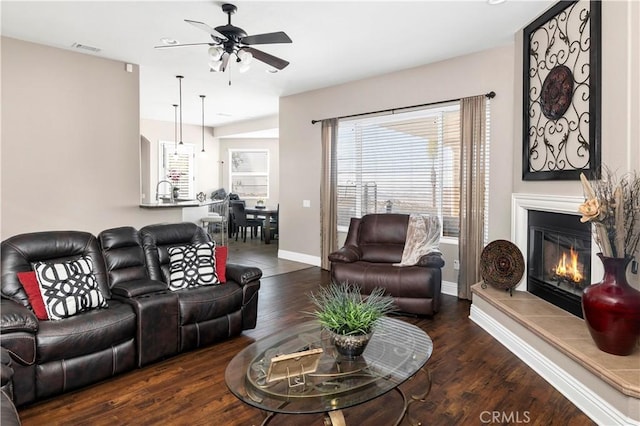 living room featuring a glass covered fireplace, visible vents, wood finished floors, and ceiling fan