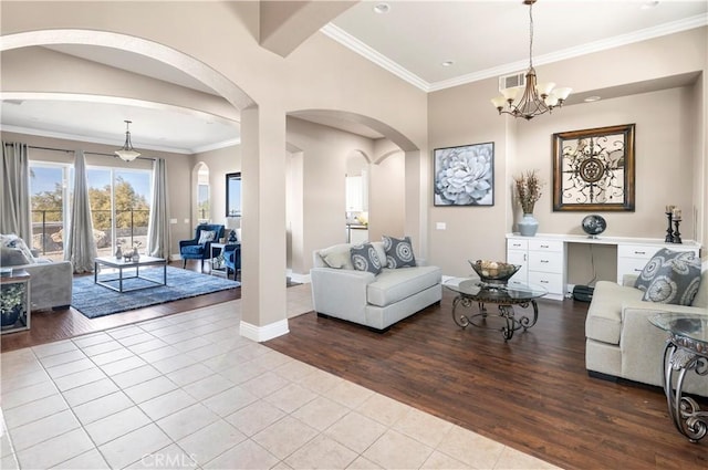 tiled living area with baseboards, visible vents, arched walkways, crown molding, and a chandelier