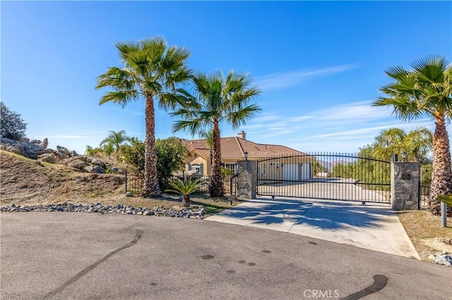 view of front of house with fence, a tiled roof, concrete driveway, stucco siding, and a gate