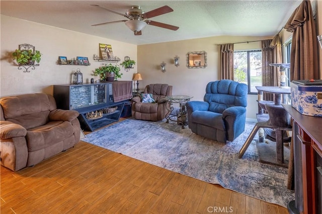 living room with a textured ceiling, lofted ceiling, light wood-type flooring, and ceiling fan