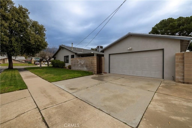 view of side of home featuring a yard, fence, driveway, and stucco siding