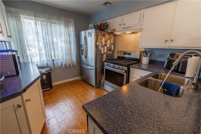 kitchen featuring visible vents, under cabinet range hood, a sink, stainless steel appliances, and light wood-style floors