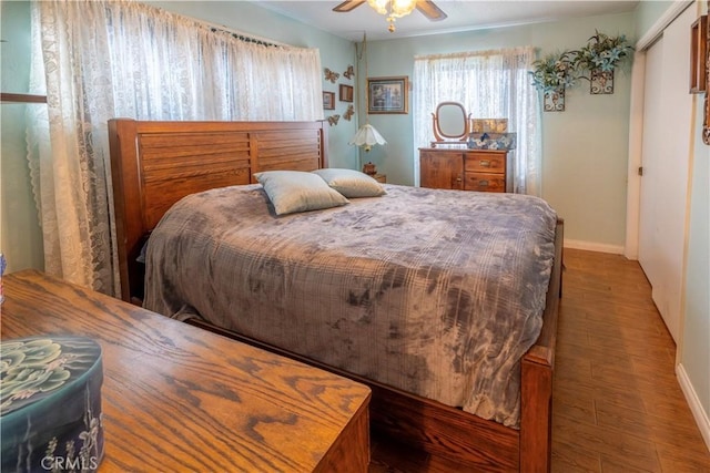 bedroom with a ceiling fan, baseboards, and wood finished floors