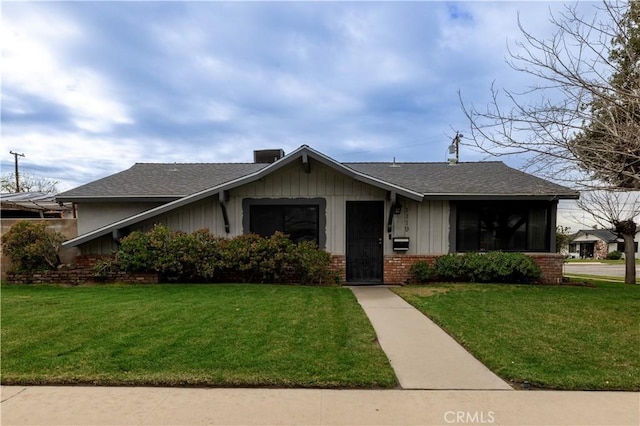 view of front of property featuring board and batten siding, a front lawn, brick siding, and a shingled roof