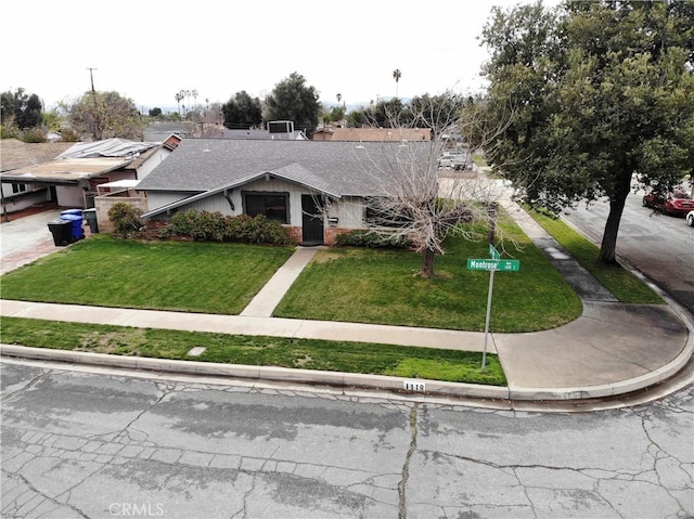 view of front of home featuring brick siding, a front lawn, and a shingled roof