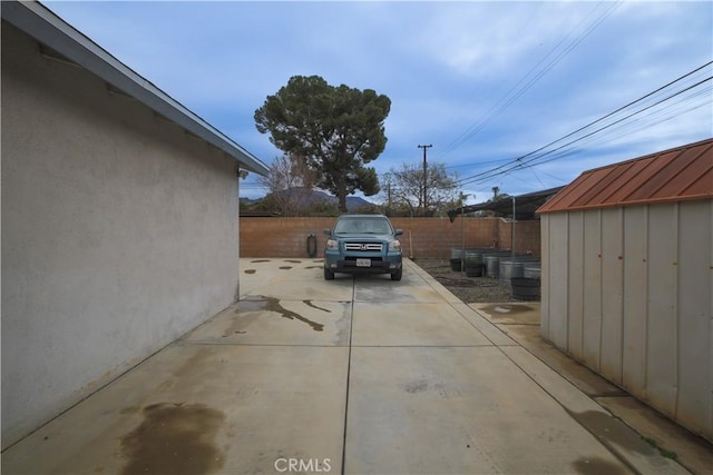 exterior space featuring a storage shed, a patio area, fence, and an outdoor structure