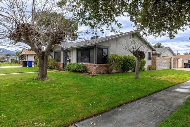 view of front facade with a front yard, an attached garage, brick siding, and driveway