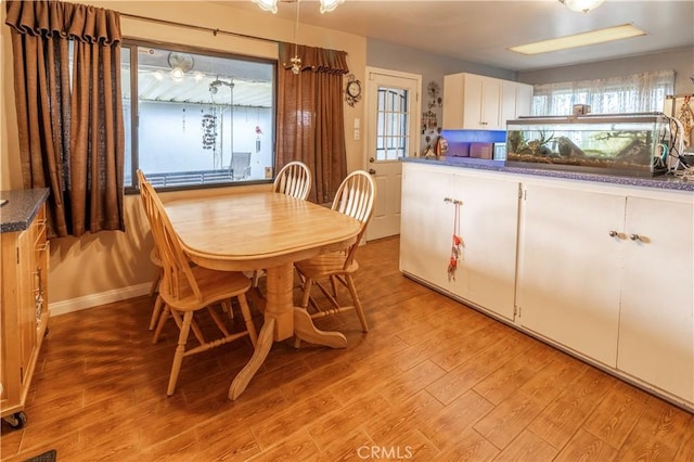 dining space with light wood-style flooring and baseboards