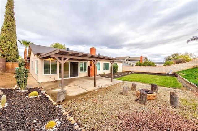 rear view of property featuring an outdoor fire pit, stucco siding, a chimney, a fenced backyard, and a patio