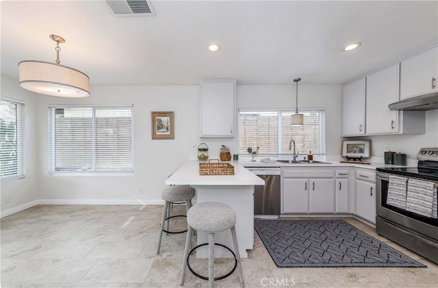 kitchen featuring visible vents, light countertops, under cabinet range hood, appliances with stainless steel finishes, and a kitchen bar