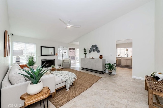 living room featuring a fireplace, a ceiling fan, baseboards, and high vaulted ceiling