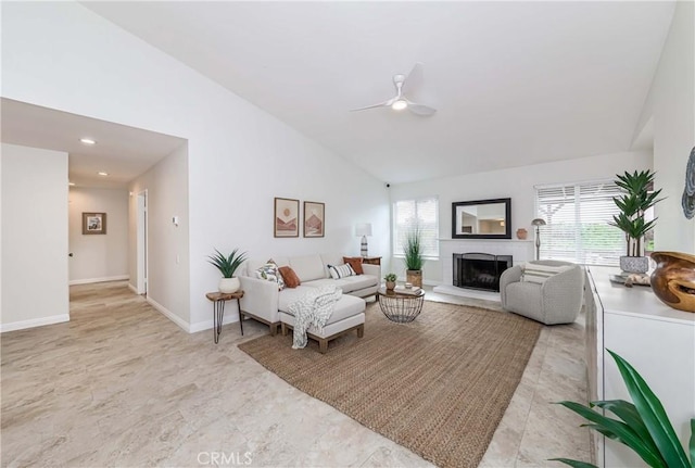 living area with a wealth of natural light, a fireplace, baseboards, and a ceiling fan