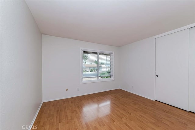 unfurnished bedroom with baseboards, light wood-type flooring, and a closet