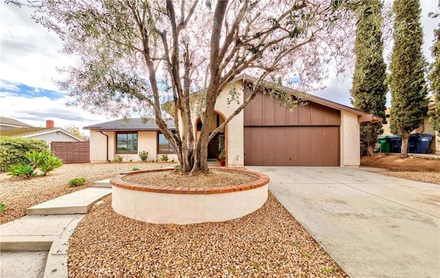 view of front of home featuring concrete driveway, fence, a garage, and stucco siding