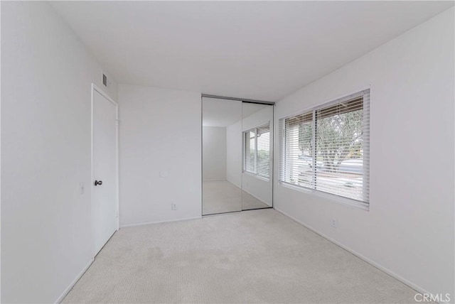 unfurnished bedroom featuring carpet flooring, visible vents, and a closet