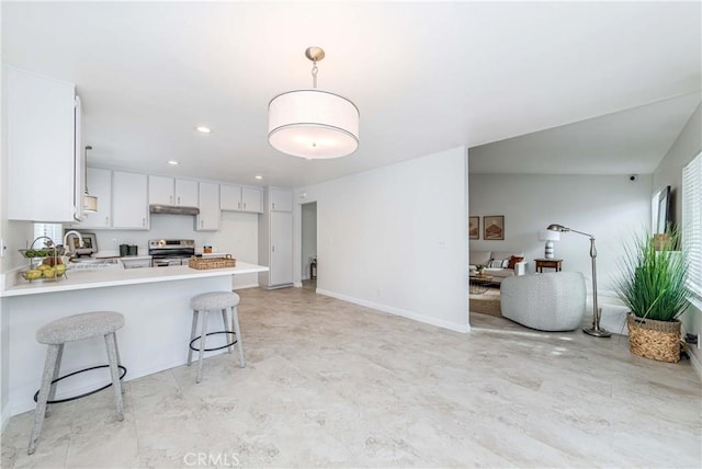 kitchen featuring a breakfast bar, a peninsula, stainless steel electric range, light countertops, and open floor plan