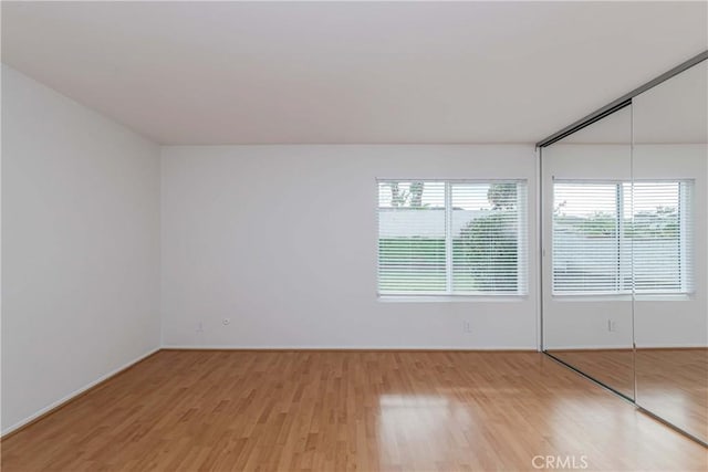 spare room with baseboards and light wood finished floors