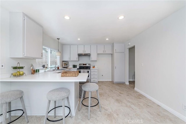 kitchen with under cabinet range hood, light countertops, a kitchen breakfast bar, stainless steel electric range, and a peninsula